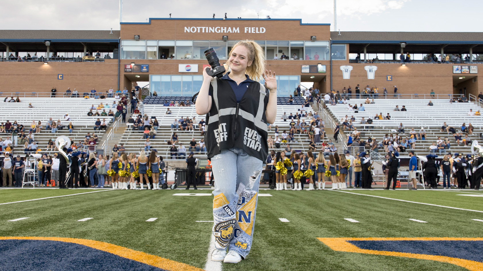Lexie Martin holding up a camera and smiling in the middle of Nottingham Field
