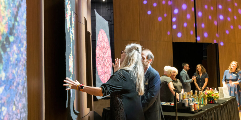 People looking at Lydia Ruyle's art on a wall