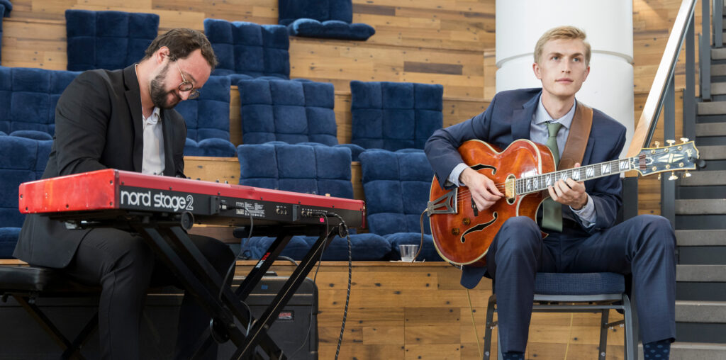 One person making music on the keyboard and another on the guitar