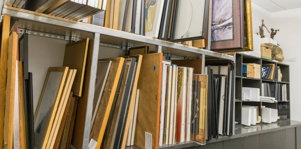 A lot of framed art stacked on a storage