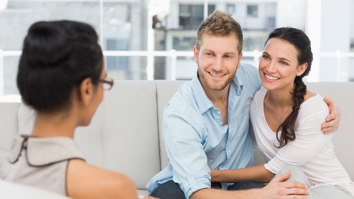 Couple, smiling, talking to a therapist.