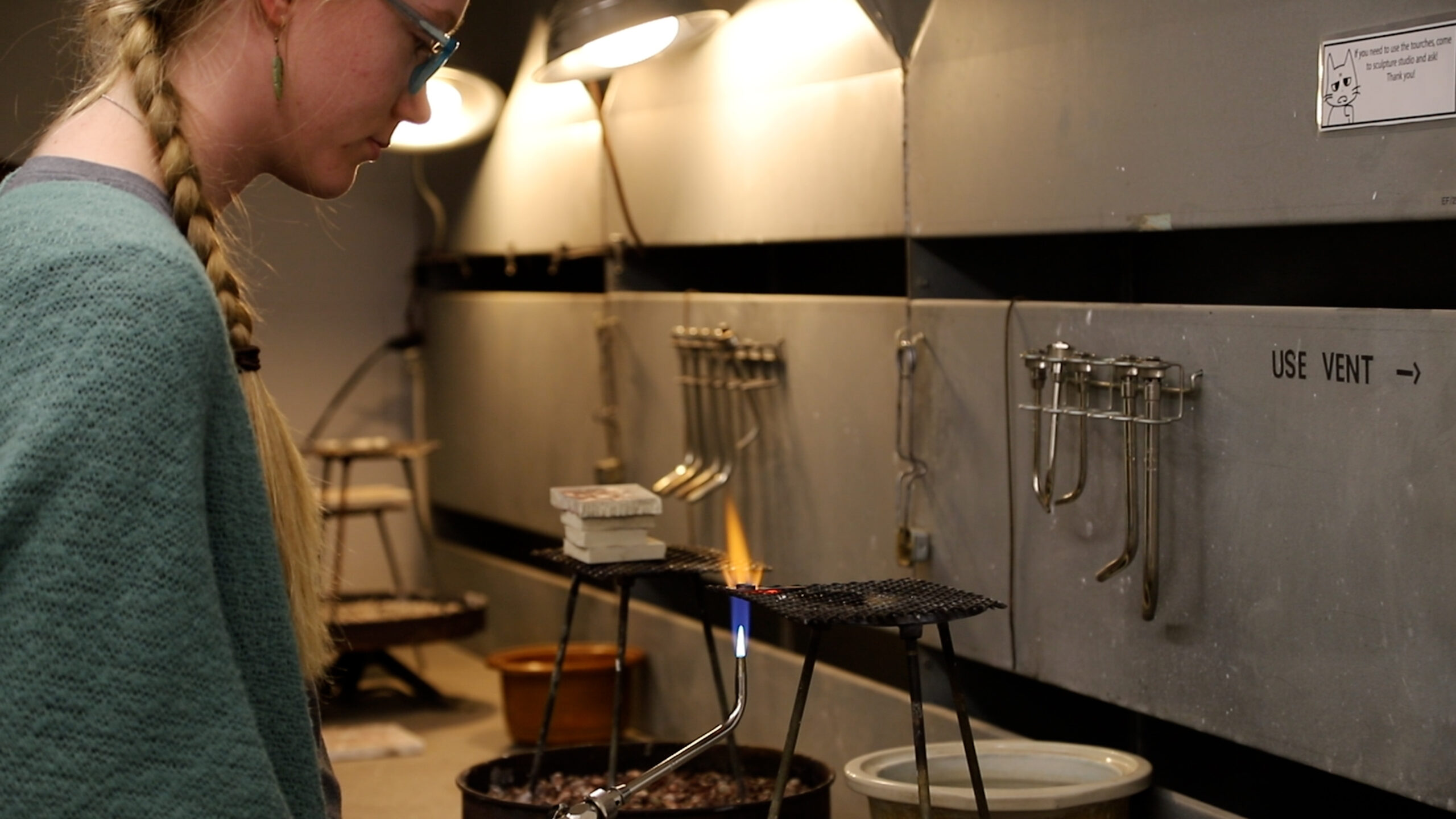 A UNC student using fire to solder metal