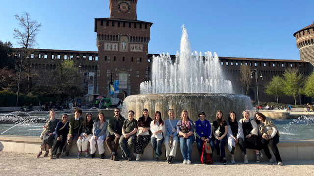 A group of UNC students sitting on a ledge in front of a castle in Italy