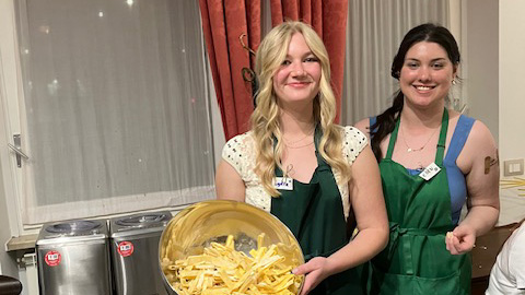Lydia Ericson (left) and Eden Trujillo (right) holding a bowl of pasta