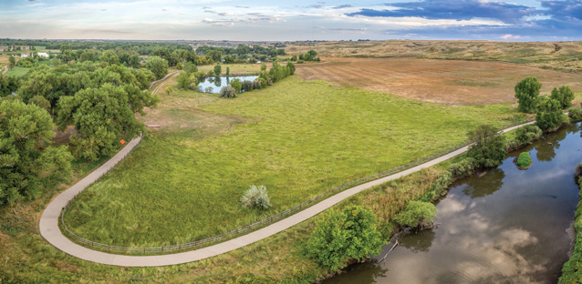 A birdseye view of the Poudre River trail next to green grass
