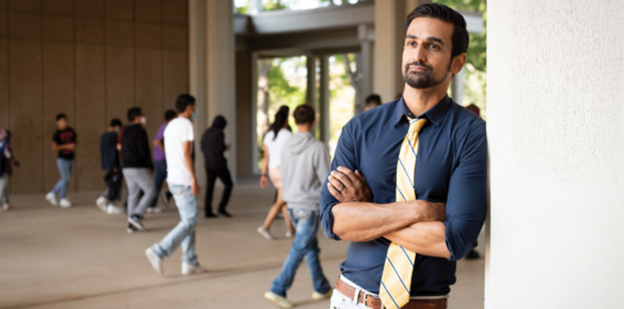 Prateek Dutta, '08, leaning in the McKee Breezeway outdoors in a blue shirt and tie.