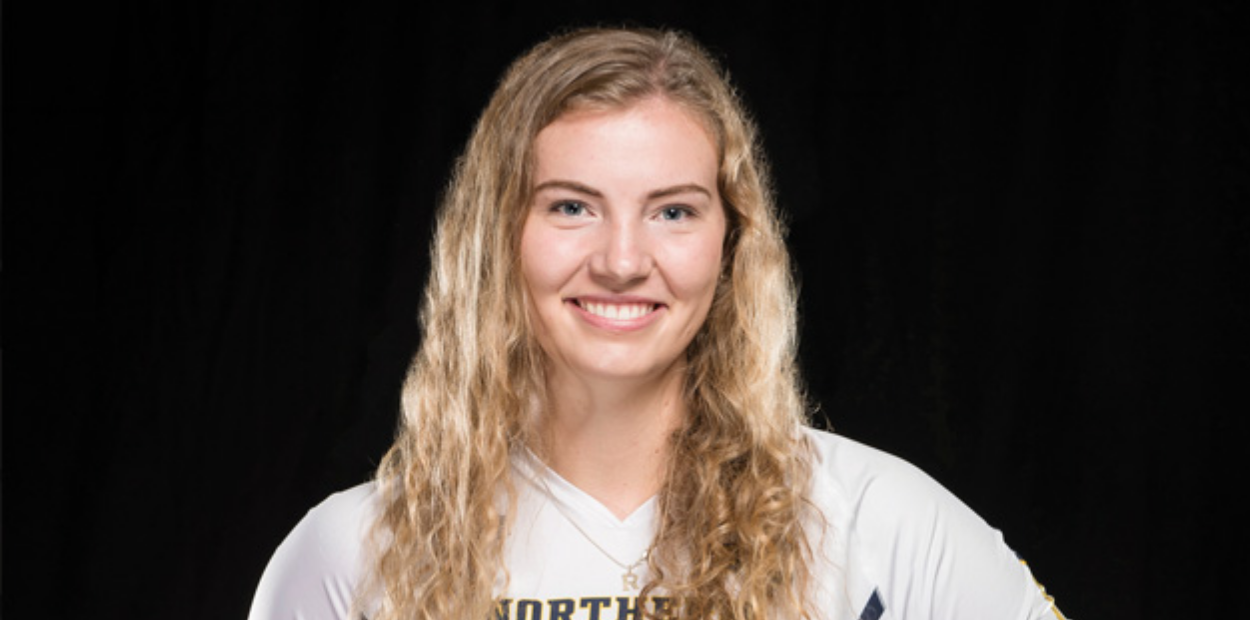 A female student athlete smiling in front of a black background.