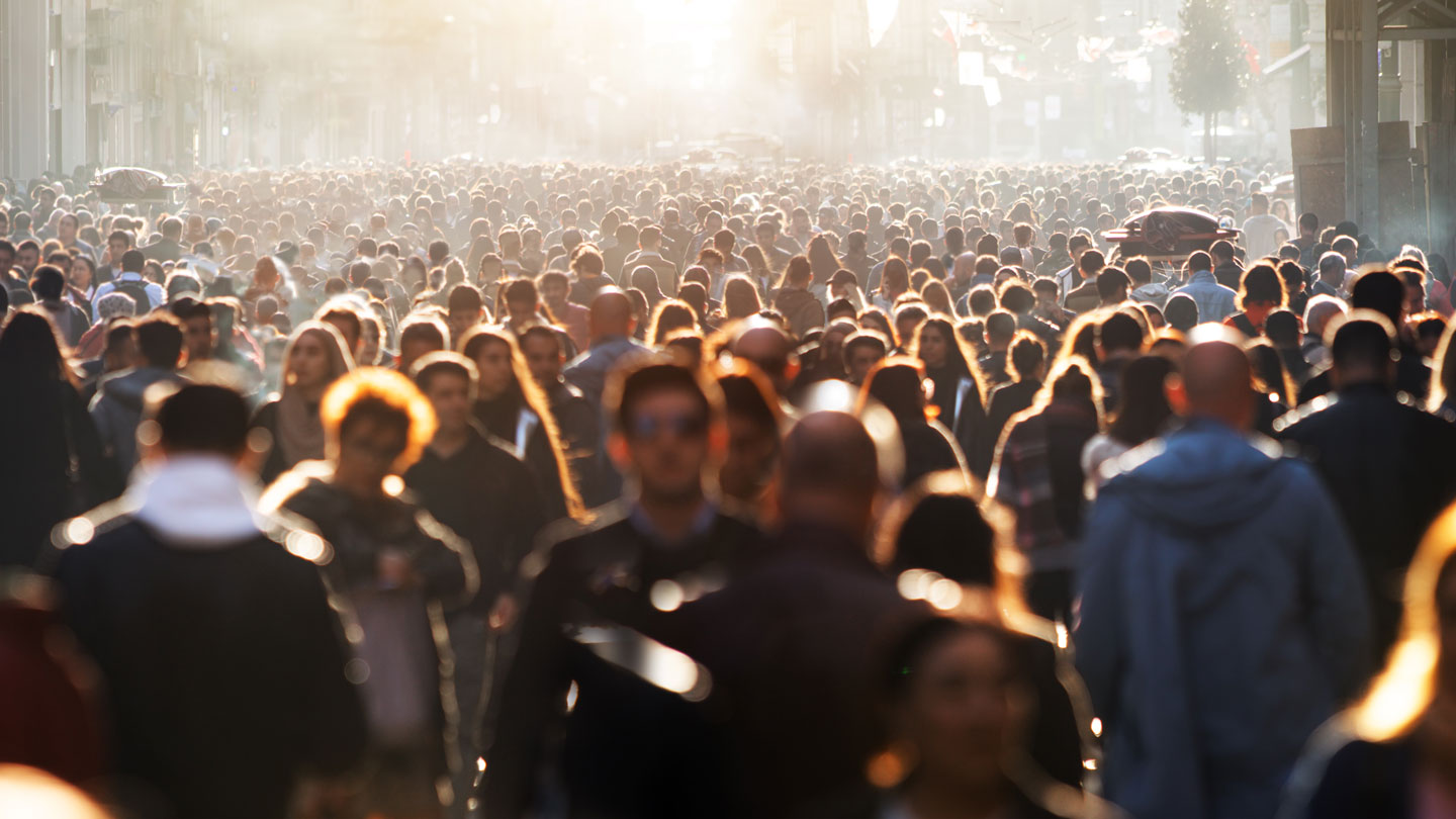Crowd of people walking on street.