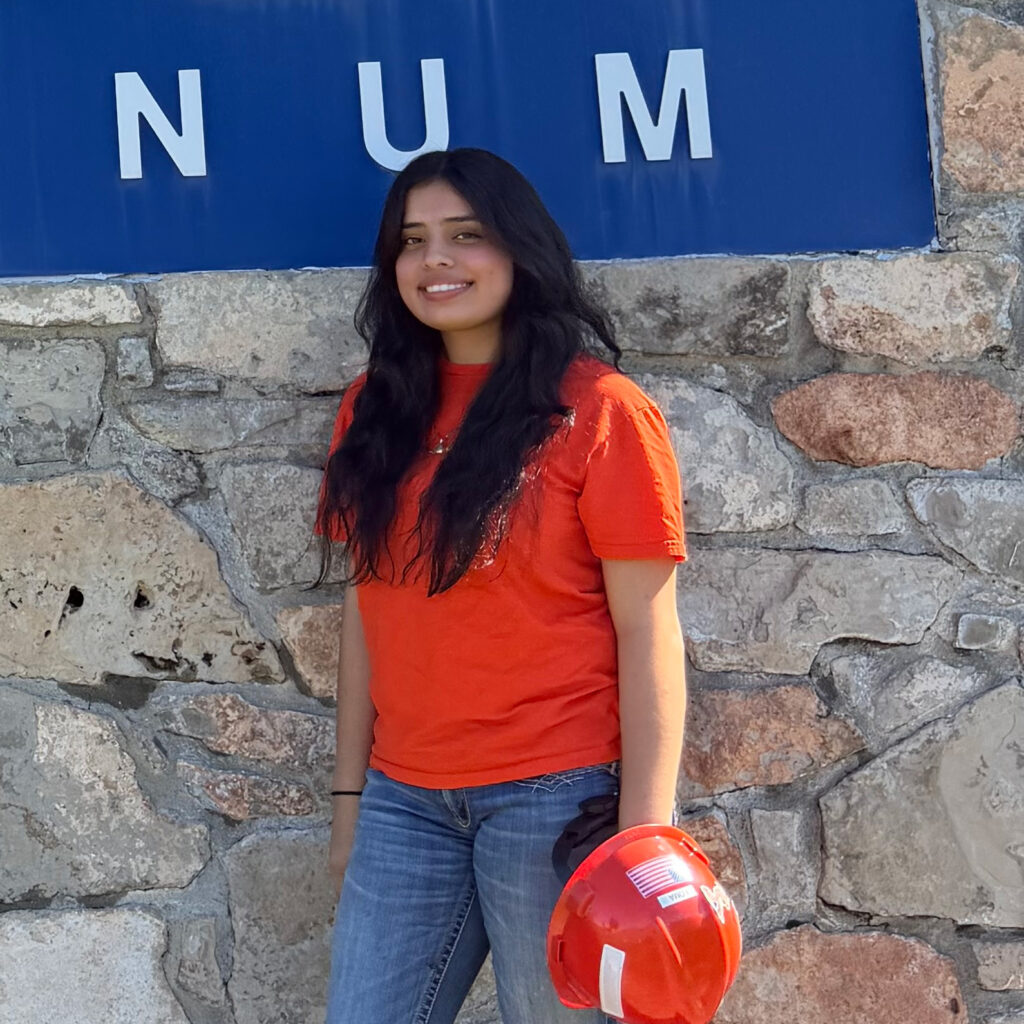 Sonia Loma wearing an orange shirt and holding an orange hard hat