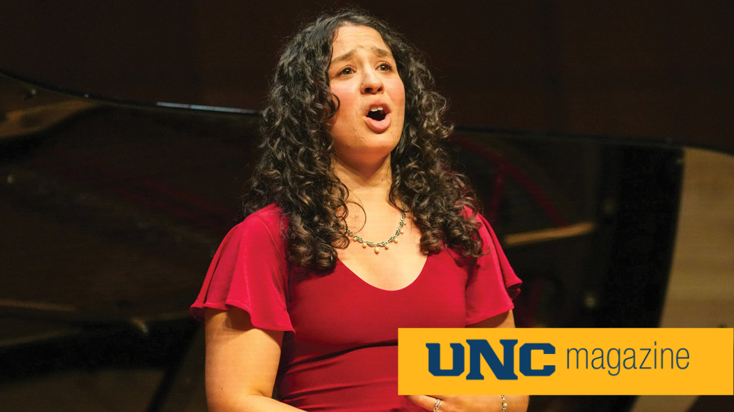A woman in a red dress singing on stage.