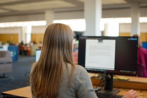 Student sitting at a computer in the open first floor area of Michener Library