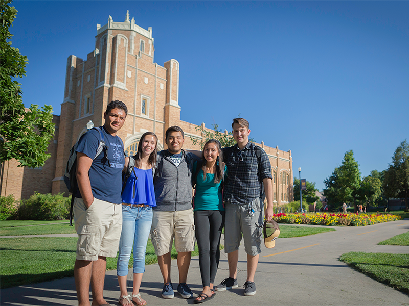 Four students standing in front of Gunter Hall in the spring.