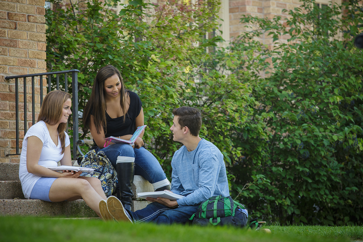 Three students sitting outside studying and talking.