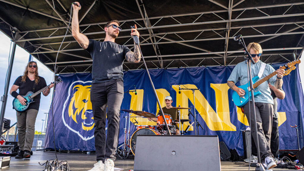 A band playing on a stage with a UNC banner behind them
