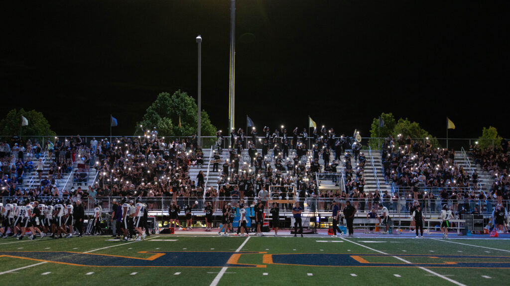 UNC football crowd holing up lights in the bleachers