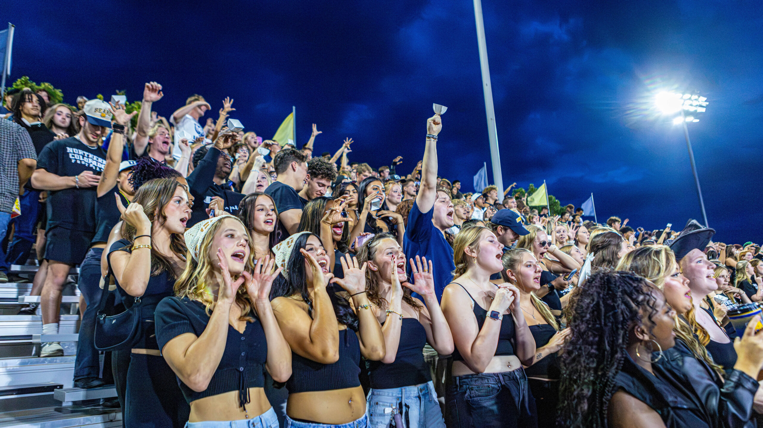 UNC students cheering on a football team in the bleachers at night