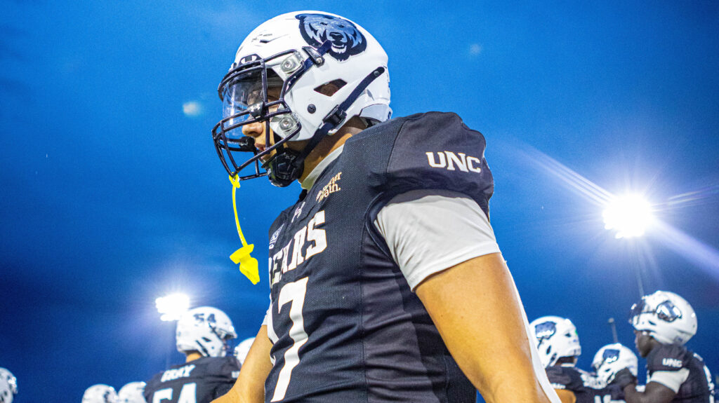 A UNC football player in his uniform with lights in the background