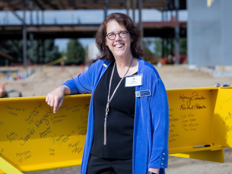 Dean Beth Longenecker stands with the final beam of the new College of Osteopathic Medicine building before it is placed.