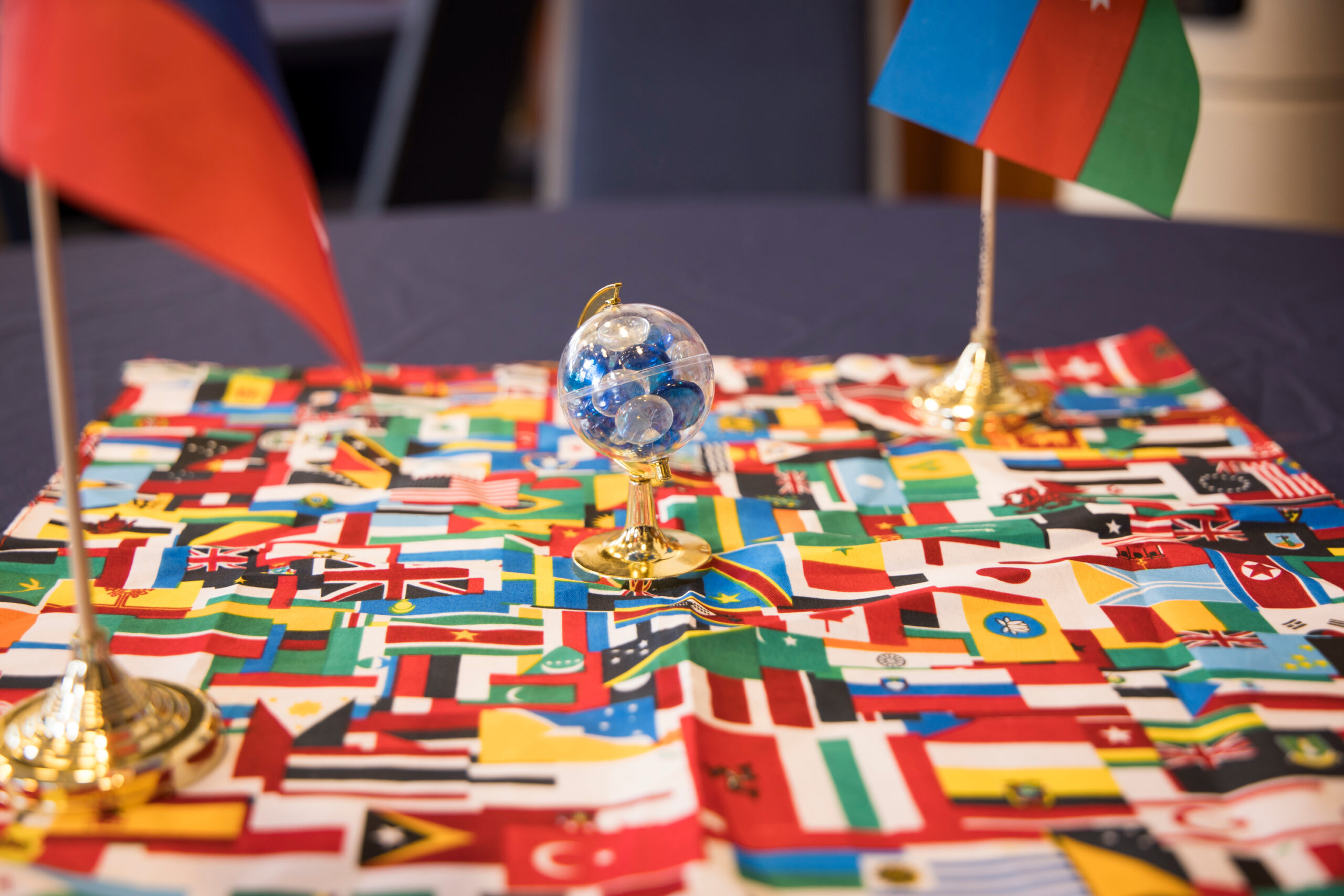Image of a mini globe on top of a tablecloth of flags