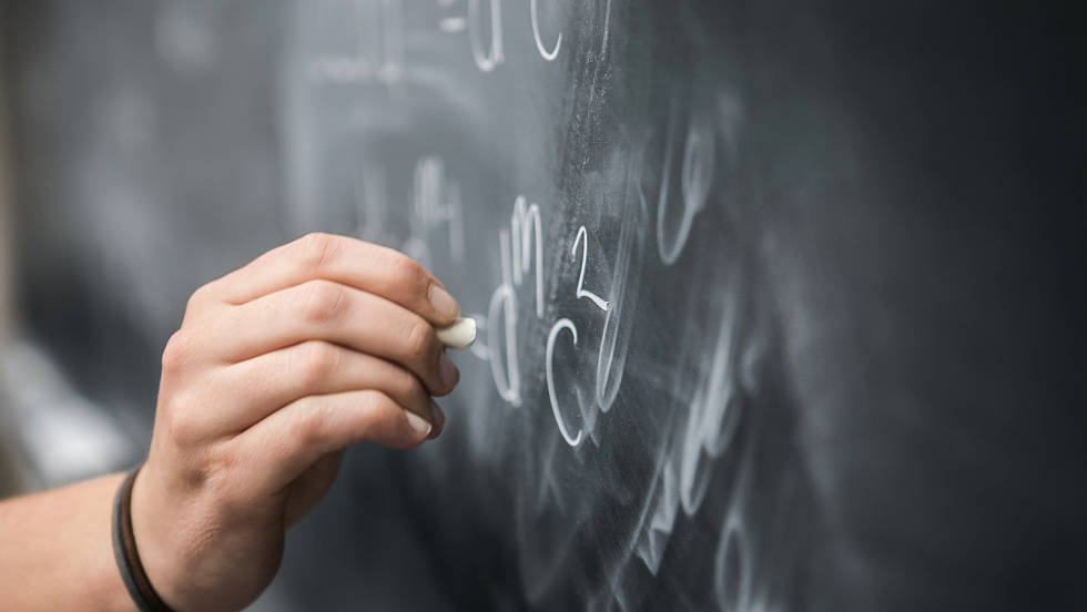 Person writing on a chalkboard