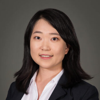 A woman with a white shirt and black jacket smiling for a photo