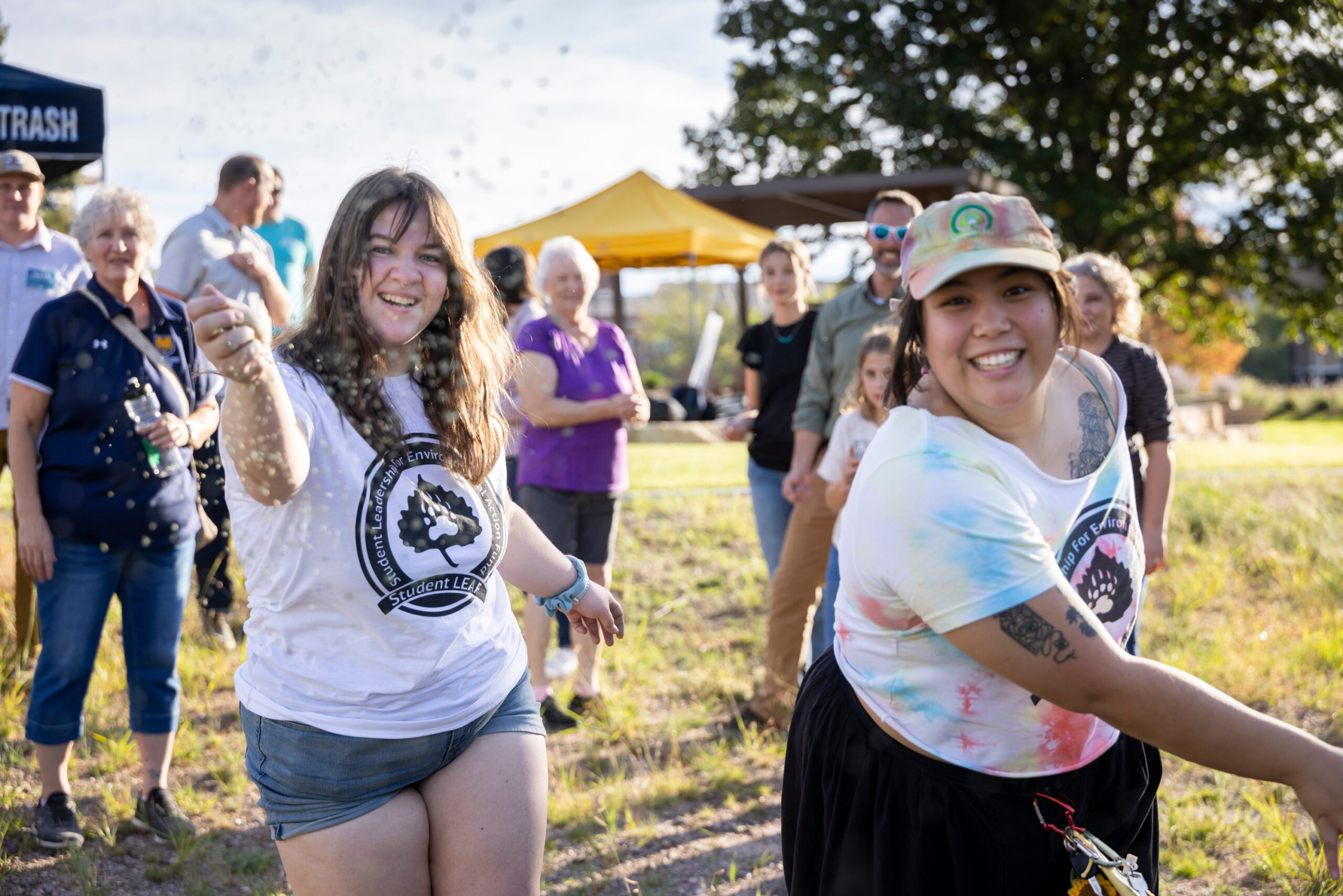 Two people throwing seeds toward the camera