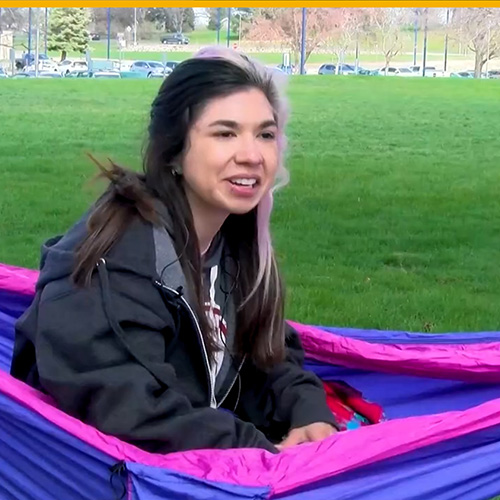 A student laying in a hammock on campus.