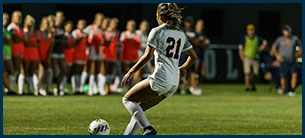 Number 21 women's soccer athlete kicking the ball down the field.
