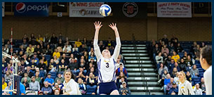 Number 3 volleyball setter goes up to set the ball at the net.