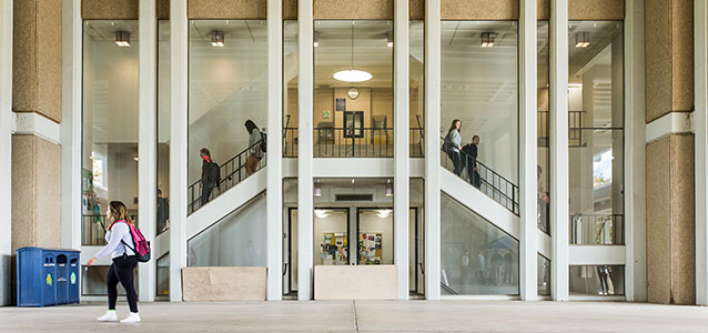 View of students walking down symmetrical stairwell behind windows