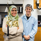A professor and her student stand with equipment in a biology lab.