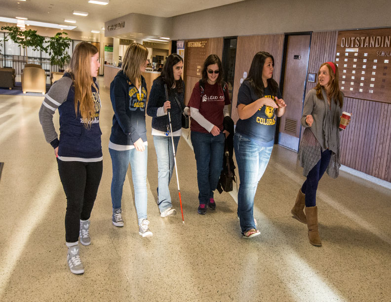 Group of students walking down hallway in campus commons building.