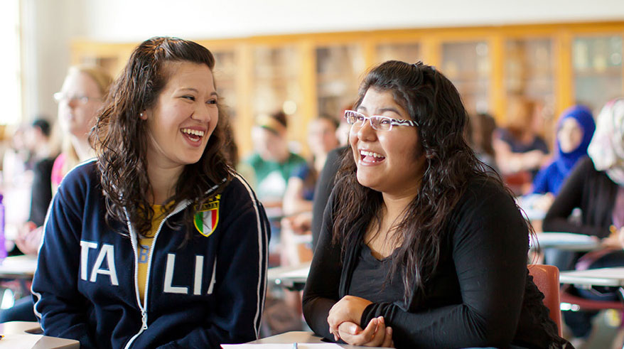 Two students laughing in a classroom.
