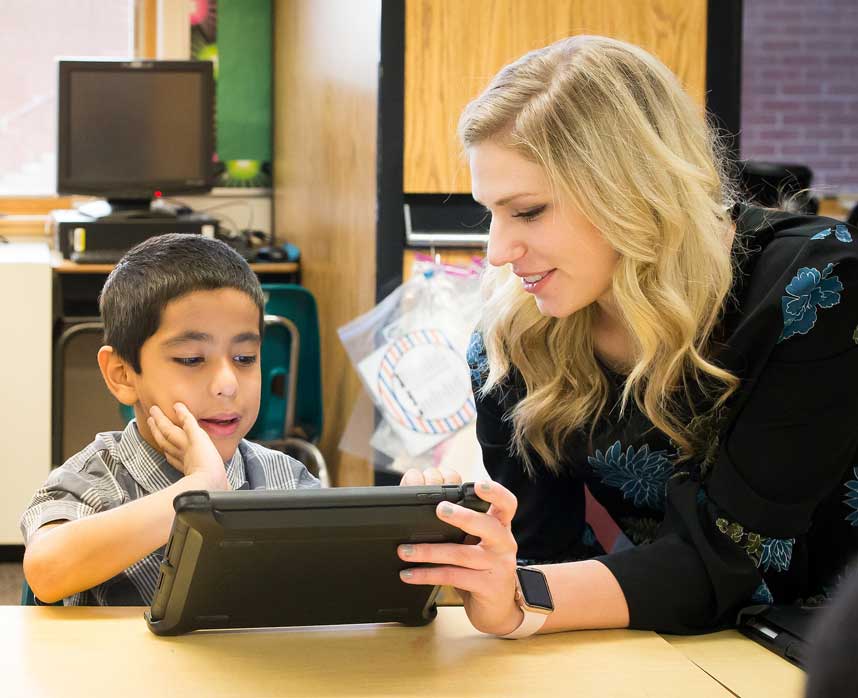 Teacher working with young student on an ipad in the classroom.