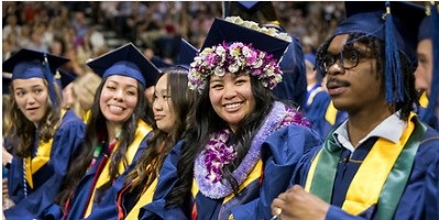 Students wearing blue graduation caps and gowns seated during Commencement