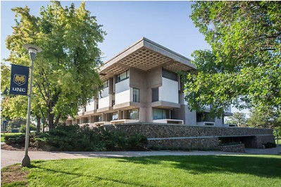 Exterior of Michener Library with green trees and UNC banner in the foreground