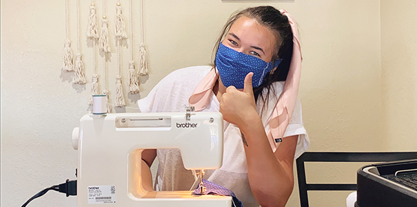 Ashley Buchholz wears a mask while sitting behind her sewing machine.