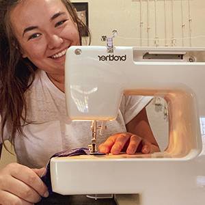 Ashley Buchholz smiles from behind her sewing machine.
