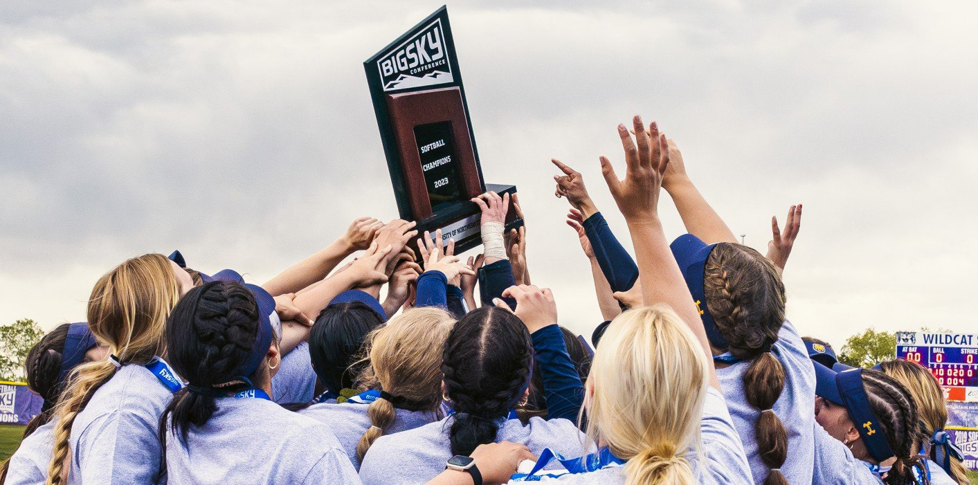 Members of the softball team holding the Big Sky Championship trophy over their heads