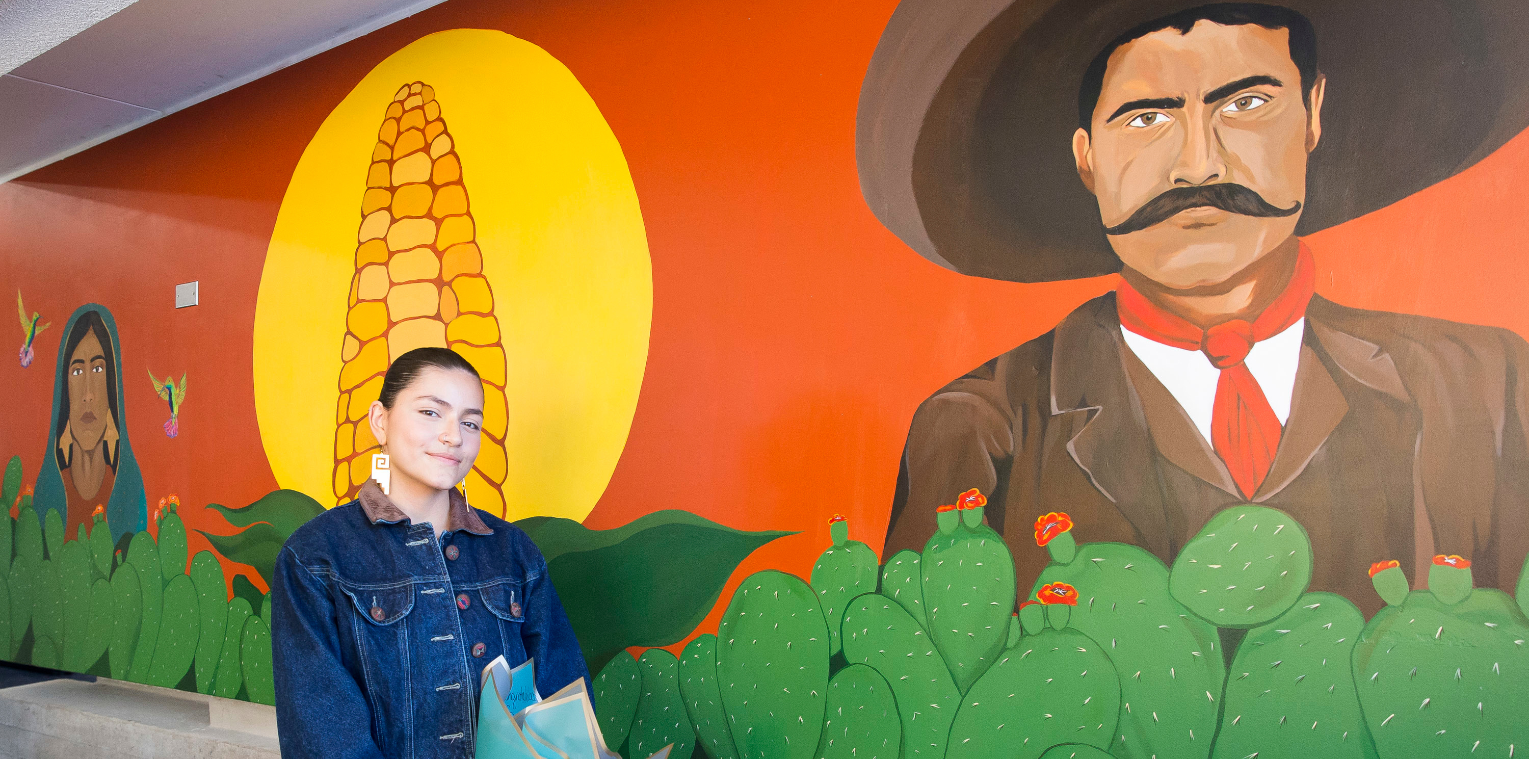 Brenda Vargas standing in front of her colorful mural.