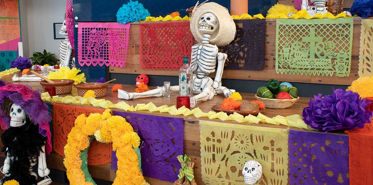 Bright Day of the Dead altar with pictures, candles and decorations on it.