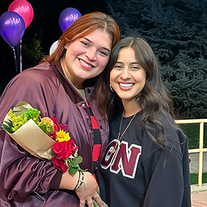 Ailin Amaro and Diana Muñoz hugging each other and holding a flower bouquet