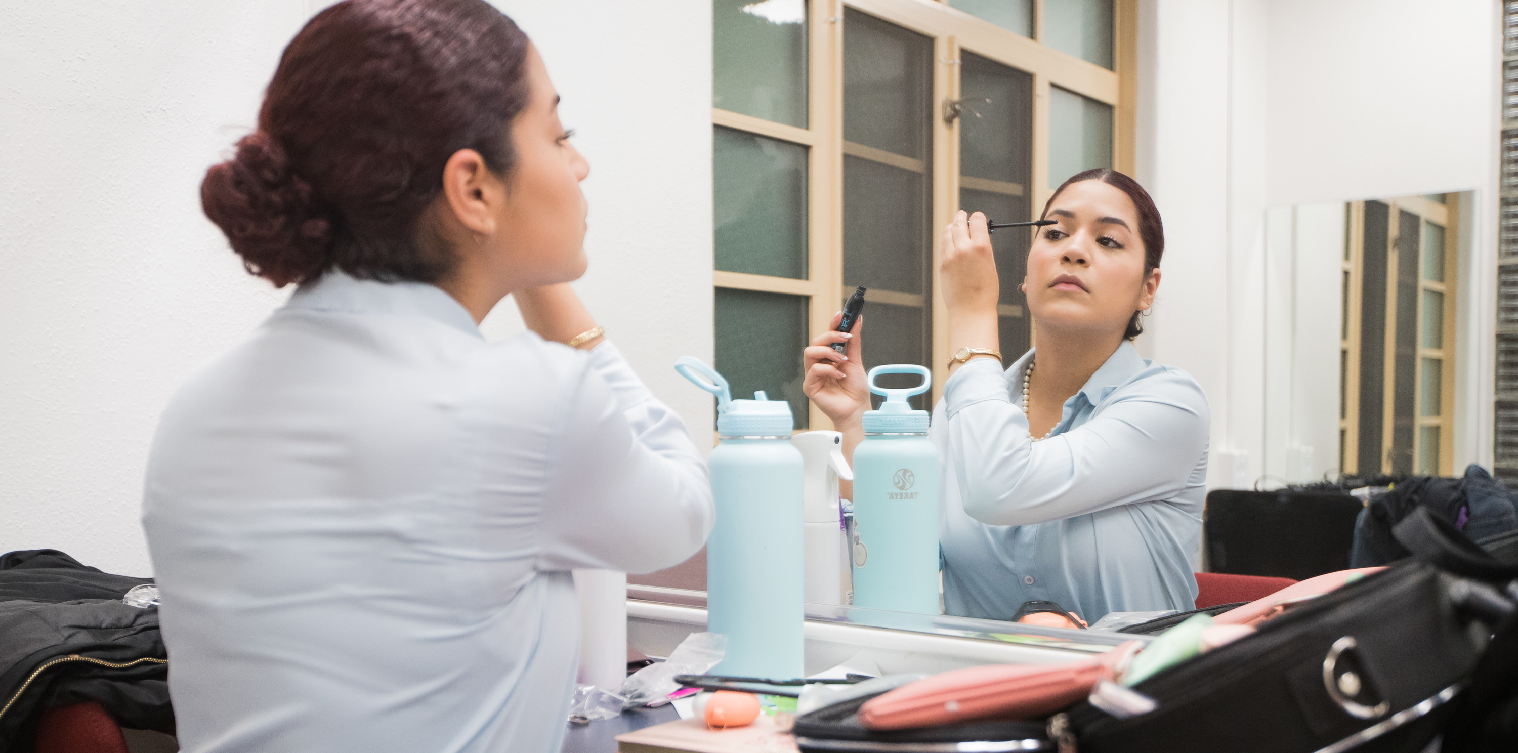 Andrea Camacho putting on mascara in the mirror