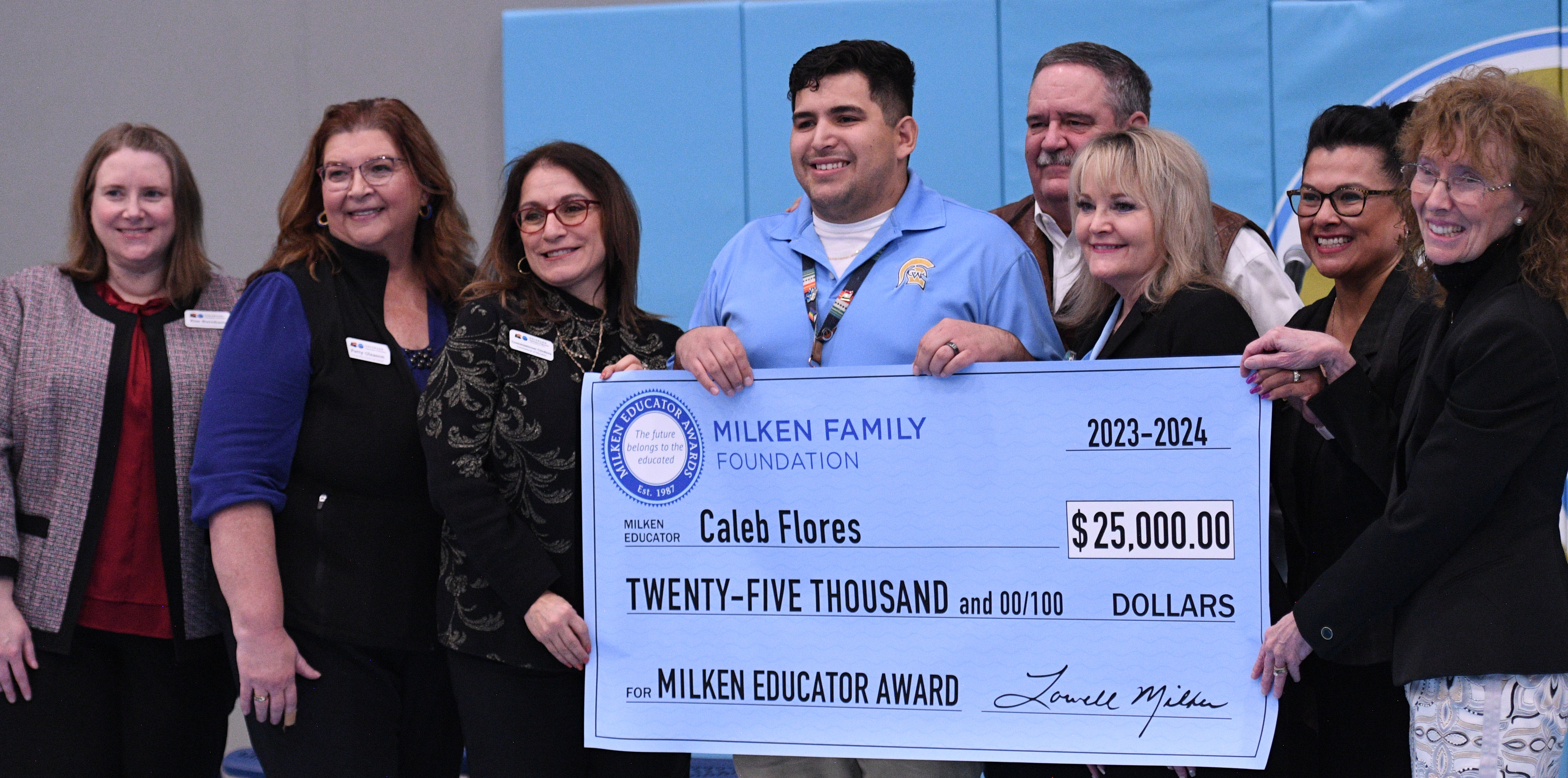 Caleb Flores junto con miembros del premio Milken y autoridades escolares deteniendo un gran cheque de 25 mil dolares