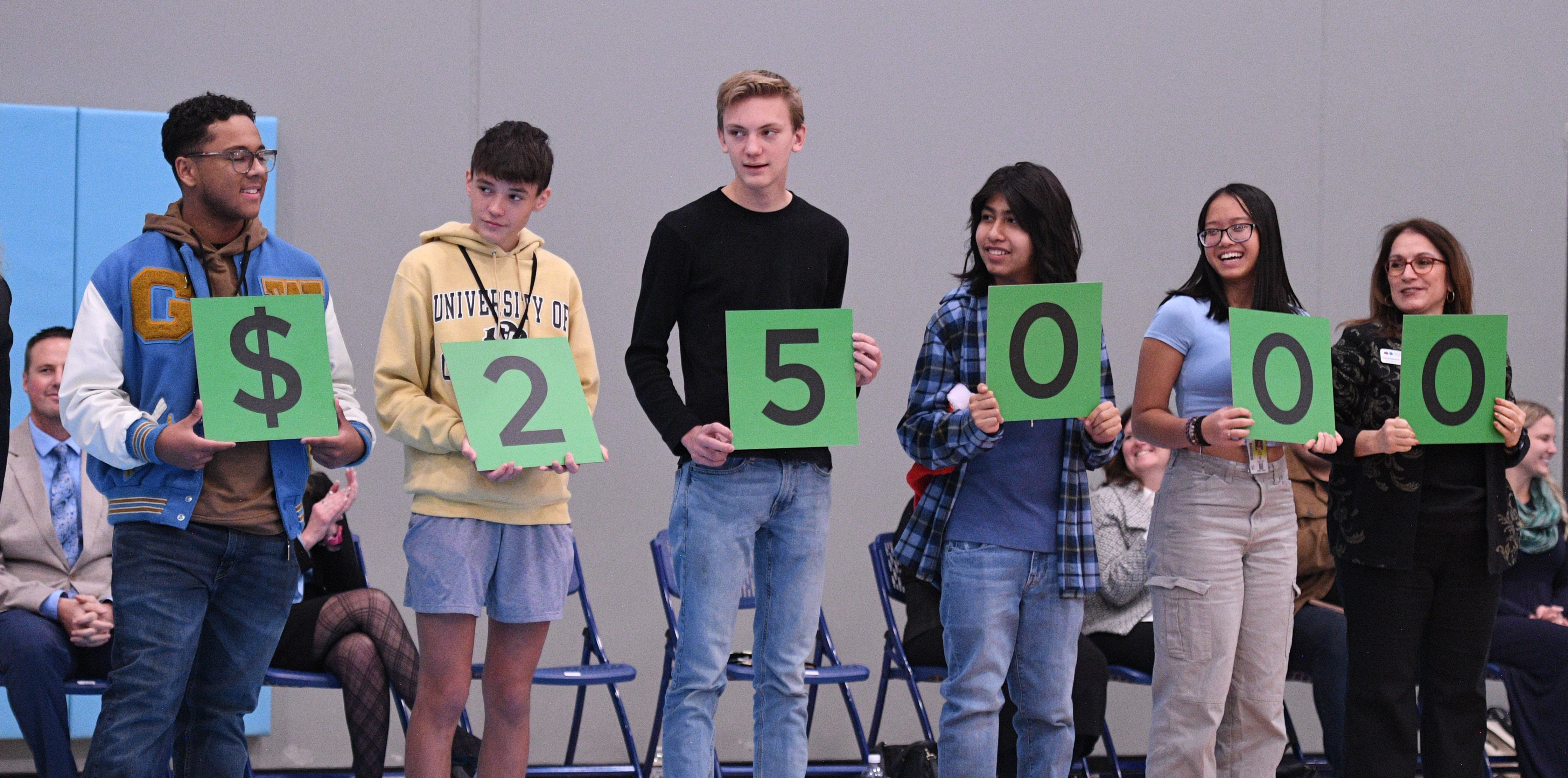 Alumnos de West Greeley sosteniendo cada uno un papel con la cifra total de 25 mil