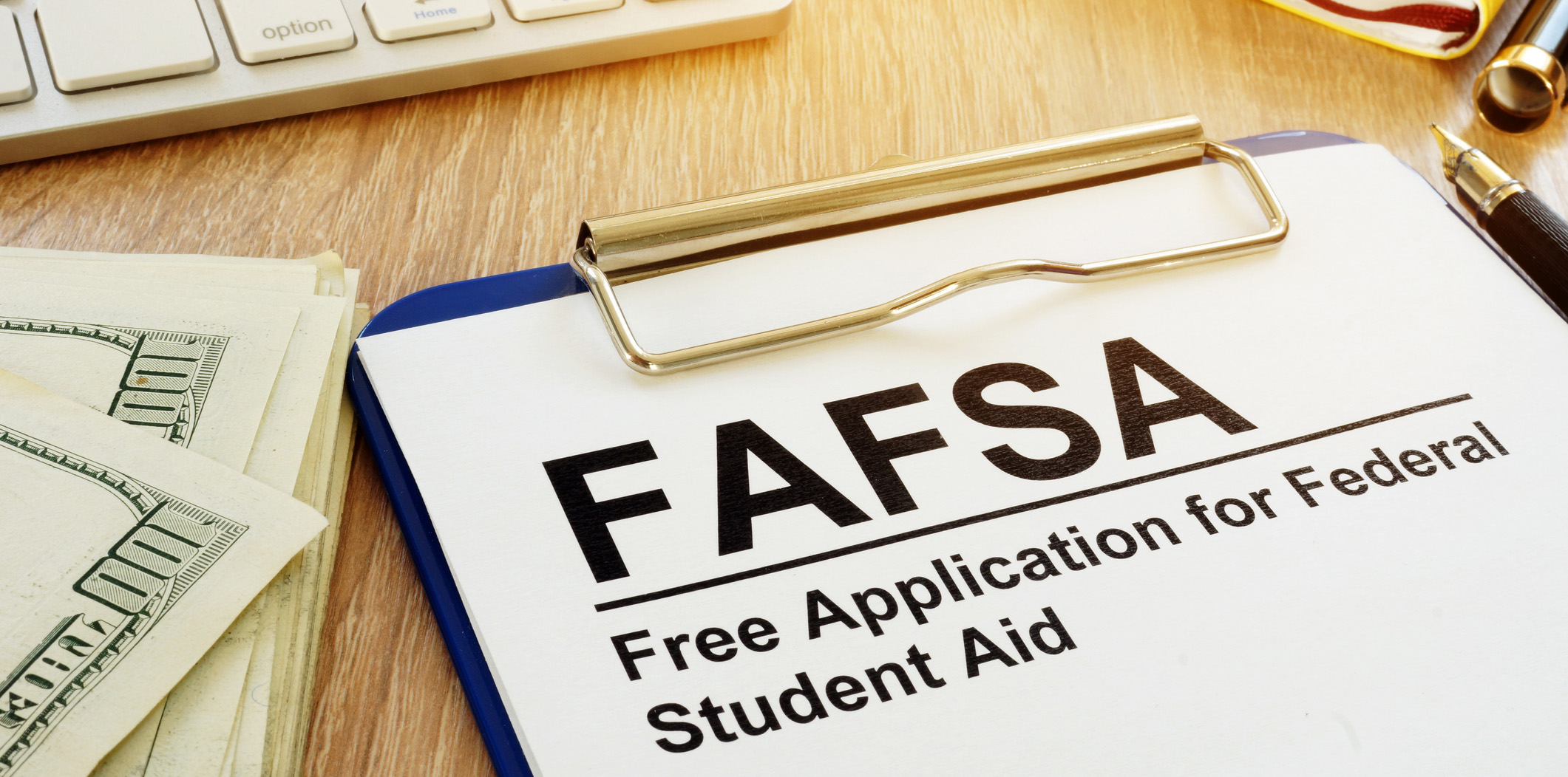 FAFSA written on a piece of paper next to money and a keyboard