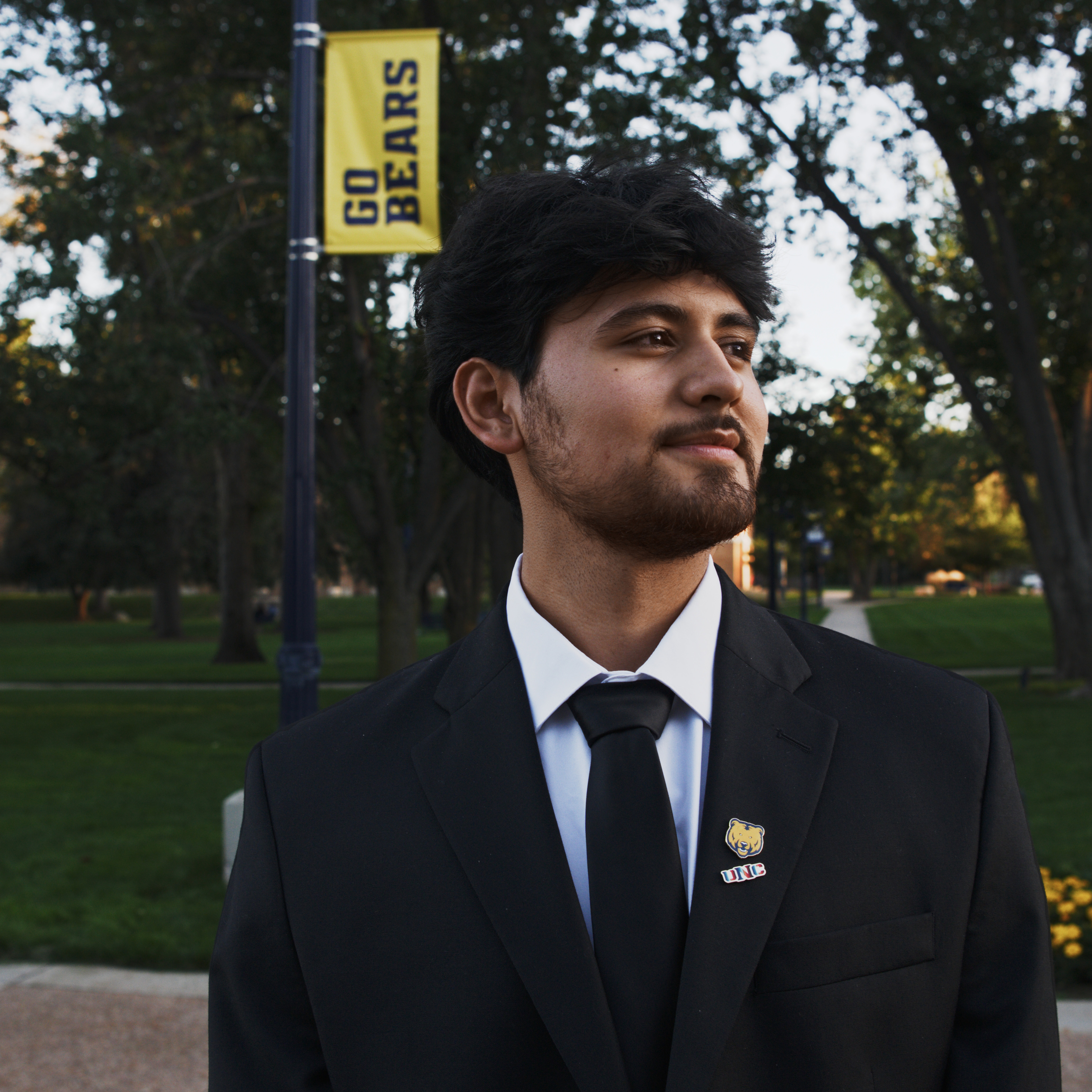 Gamaliel Ayala looking to the left outside with a UNC flag in the background