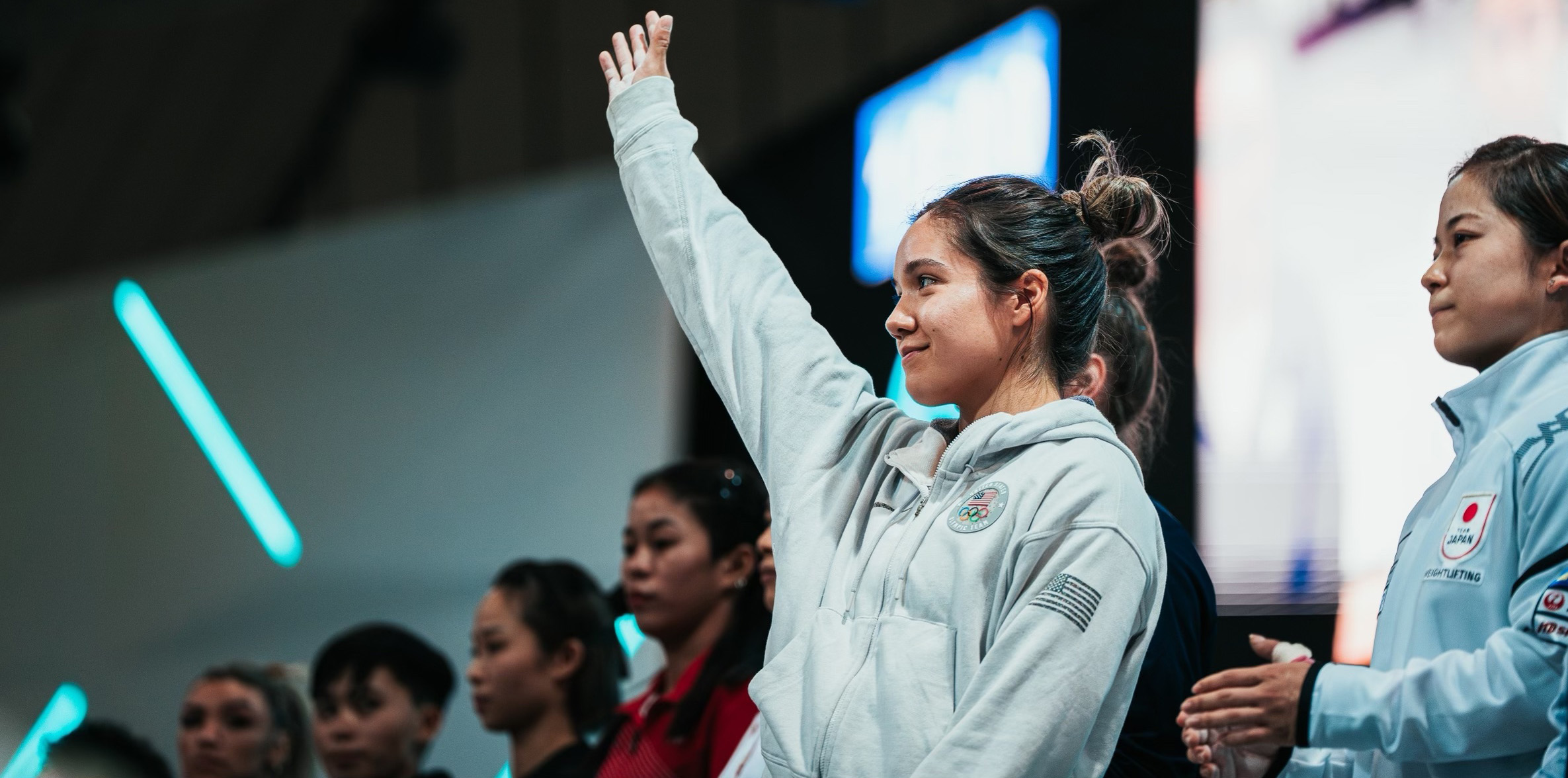 Jourdan Delacruz standing with her arm up waving