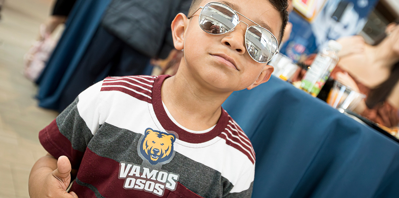 boy with sunglases and a t-shirt that says Vamos Osos