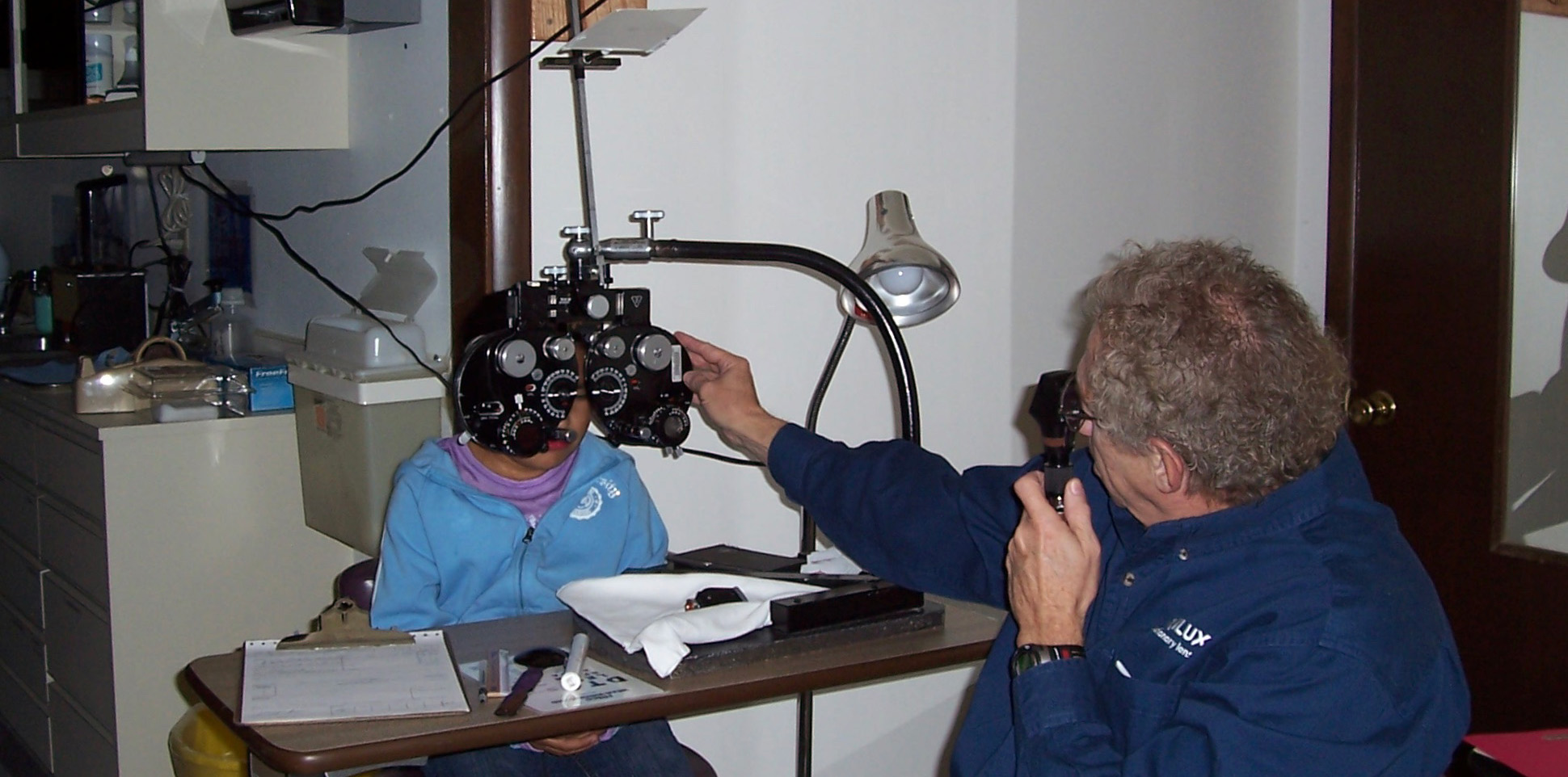 Lavaux performs an eye exam on a child at the St. Labre Indian School in Ashland, Montana in 2003